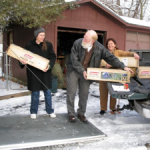 Janet, Bill, and Terry loading tents into a trailer