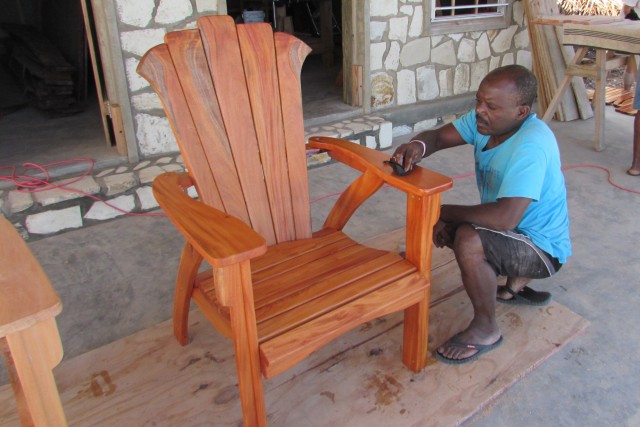 Christophe oiling a chair made in the wood shop