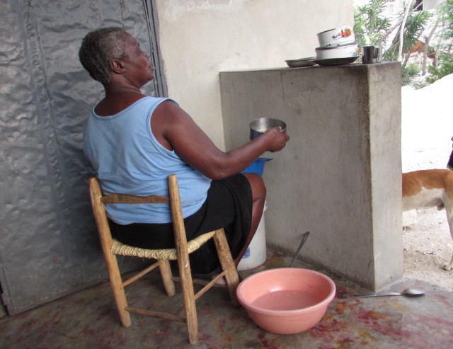 Madame washing her dishes in a bucket on her newly smoothed wall porch!