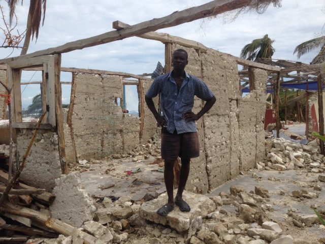 A man standing in the ruins of his home in Odo Kashiman